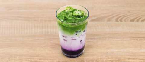 Iced Blackberry matcha latte in glass on a wooden surface